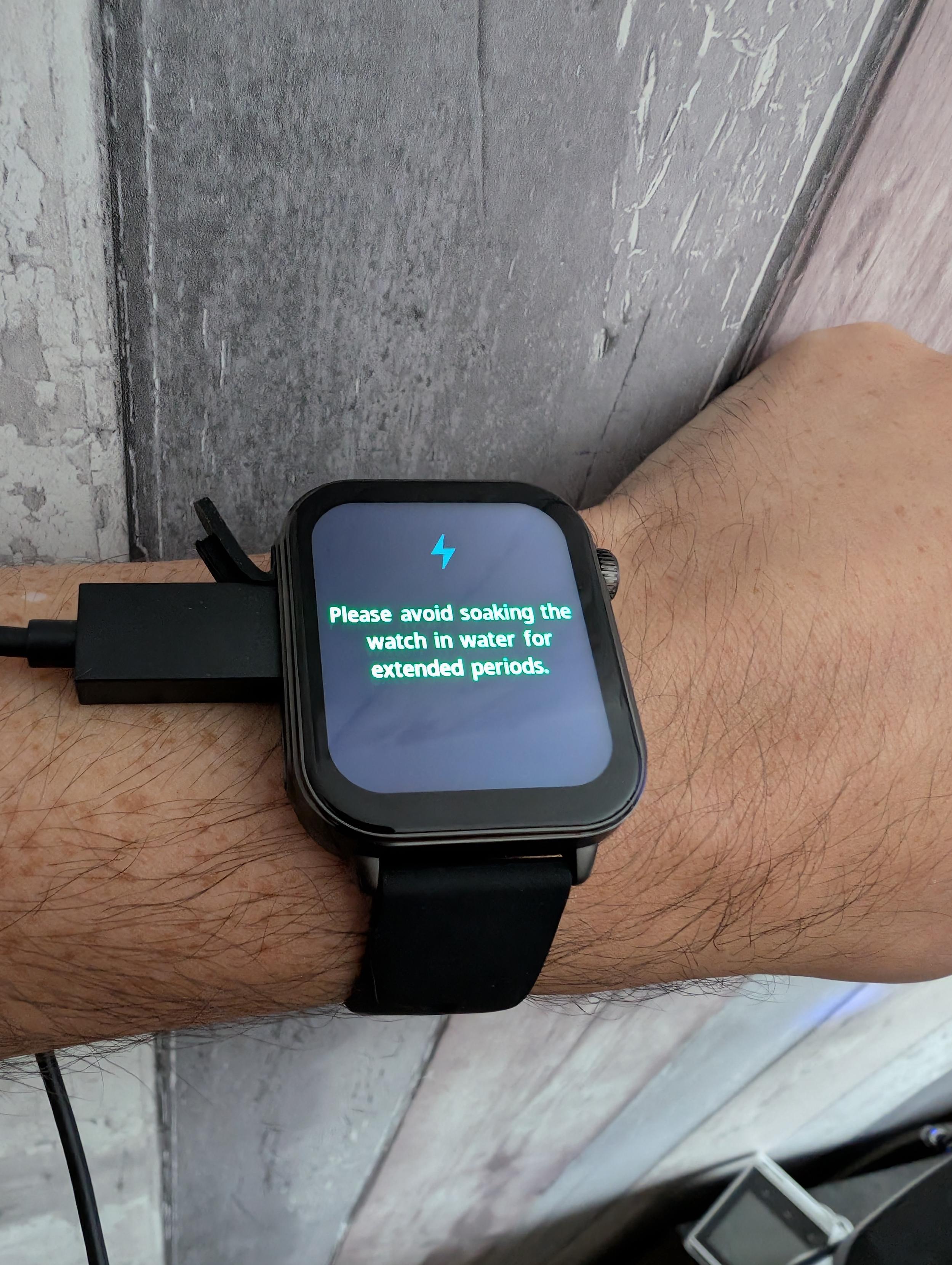 Smart watch on my wrist with a USB-C cable plugged in to it.