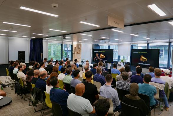 Photo of the audience from the rear with MC Richard speaking.