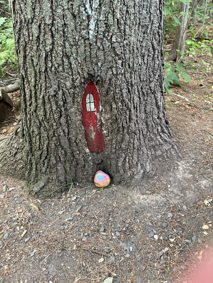 A red faerie for with a painted rock in front. 