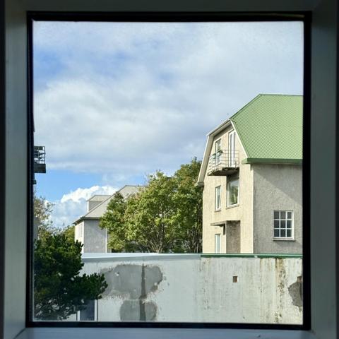 A square-ish pane of glass showing a house with a green roof and some clouds