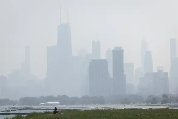 Image of an urban skyline across a small body of water heavily obscured with smoke
