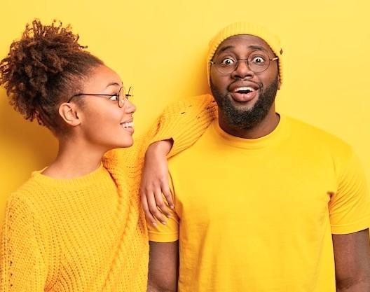 Two people having fun relating to each other all dressed in yellow and a yellow background