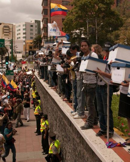 Una fila de personas con urnas electorales sobre un muro, delante de la Junta Electoral Nacional en 2013