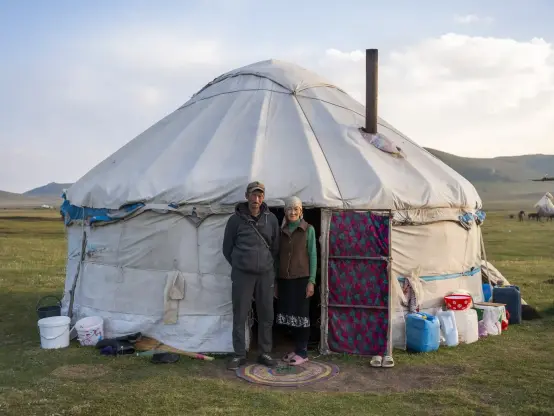 A nomadic couple pose in front of their yurt. 