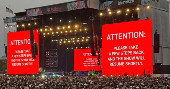 Lollapalooza 2025 stage showing a message on the jumbotrons: Attention: Please take a few steps back and the show will resume shortly.