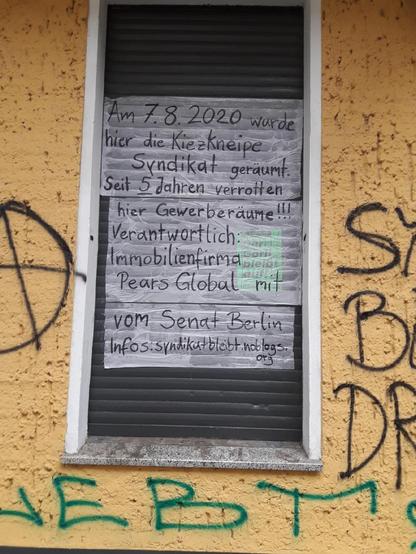 Tapete mit folgendem Text auf einem Rollladen des alten Syndi:
Am 7.8.2020 wurde hier die Kiezkneipe Syndikat geräumt. Seit 5 Jahren verrotten hier Gewerberäume!!!
Verantwortlich Immobilienfirma Pears Globsl mit Hilfe des Berliner Senats!