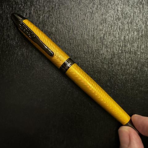 Conklin Herringbone yellow fountain pen. Accents are a dark metal color - between brown and black. The body of the pen has a herringbone pattern etched into it. .