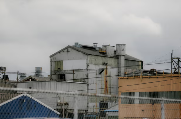 Ugly grey industrial building against an ugly grey sky with an ugly fence and ugly power lines and auxillary buildings