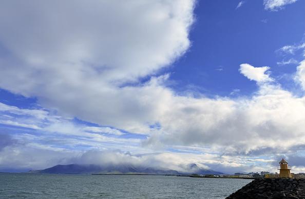 A shot of Esjan under a bit of blue sky dramatically punctuated with fluffy white clouds