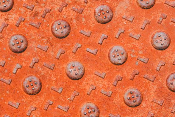 12 or so round circles with four dots on the them on a square slanted grid with L-shaped metal bumps between them on a rust red surface.