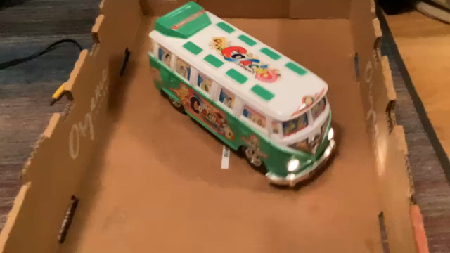 A lime green VW bus adorned in various stickers drives around while playing a peppy chiptune rendition of It’s a Small World and blinking its headlights in time. It’s driving around in a little cardboard cucumber pallet, and whenever it hits one of the edges, it turns back around and goes another direction.