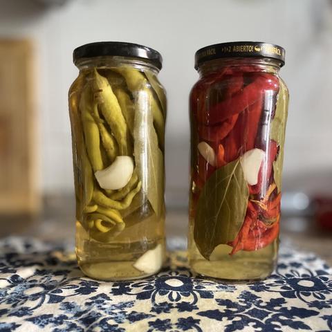  Dos tarros con guindillas en conserva de color verde y rojo.