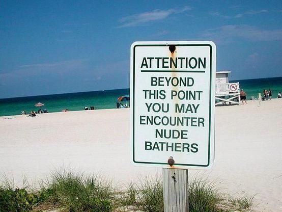 How to get attendees to risk doing something new at your event: a photograph of a sign on a beach that says "ATTENTION BEYOND THIS POINT YOU MAY ENCOUNTER NUDE BATHERS"