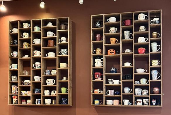 -Libreros con tazas en muro de cafetería.

-Bookcase with mugs on a cafeteria wall.