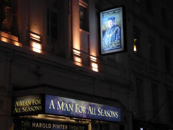 Front of Harold Pinter Theatre at night with two illuminated hoardings advertising A Man For All Seasons.