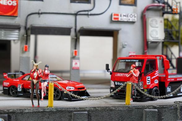 A Nissan Skyline LB-ER34 Super Silhouette by Mini GT and a Custom Tow Truck, LB Super Silhouette by Micro Turbo in 1:64 scale with 1:64 figures on AREA 164