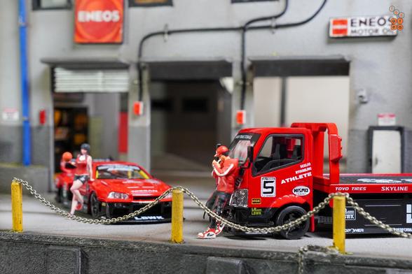 A Nissan Skyline LB-ER34 Super Silhouette by Mini GT and a Custom Tow Truck, LB Super Silhouette by Micro Turbo in 1:64 scale with 1:64 figures on AREA 164