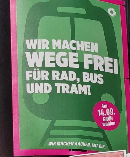 Wahlplakat von Bündnis 90/Die Grünen. Im Hintergrund eine stilisierte Tram in dunkelgrün auf hellgrünem Grund, darauf in Weiß der Spruch

Wir machen Wege frei
Für Rad, Bus
und Tram!