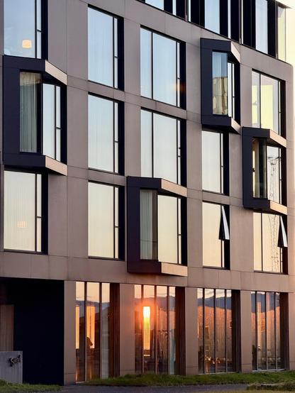 The sun shines through the glass of the dining room of Tides, the restaurant inside the Edition hotel. You can see the front of the building with a bit of the bright sunlight coming through on the ground floor. 