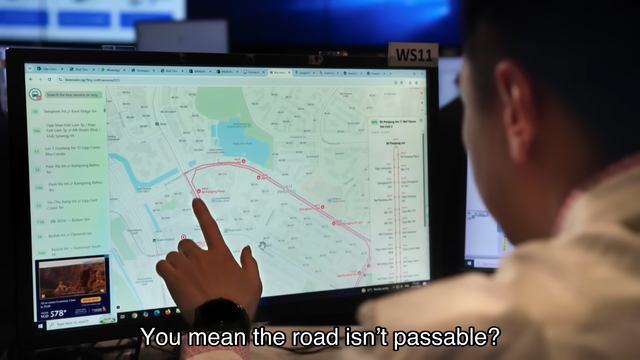 A person pointing at a computer screen displaying a bus route map with the subtitle "You mean the road isn’t passable?" at the bottom.