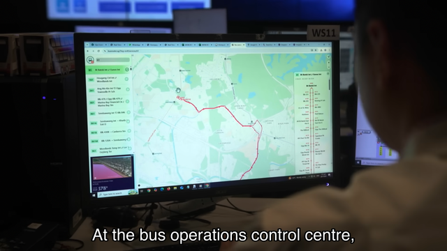 A person monitors a digital map displaying bus routes and stops on a computer screen at a bus operations control centre.