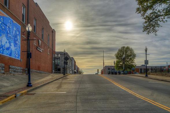 Main Street at sunset stretches uphill, lined with brick buildings under a partly cloudy sky.