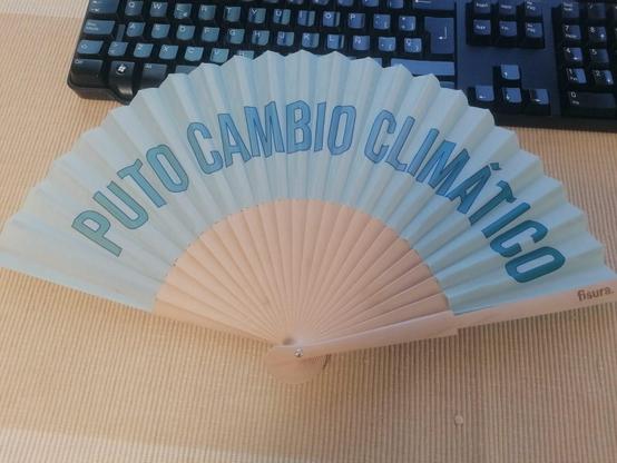 Abanico clásico de madera y con la tela en azul clarito e impreso sobre esta, en degradado de azul más oscuro, se lee: "PUTO CAMBIO CLIMÁTICO".
(Tambien se distingue la marca del fabricante: fisura)