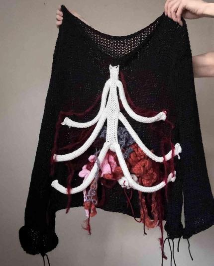 Black crocheted sweater with a white yarn ribcage and colorful yarn "organs."