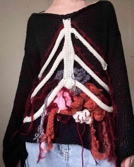 Black crocheted sweater with a white yarn ribcage and colorful yarn "organs."