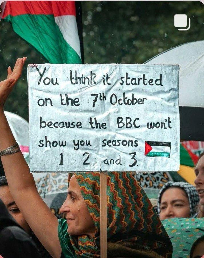 Palestine solidarity protester holding a Palestine flag and a sign
Text:
“You think it started on the 7th October
  Because the BBC won’t show your seasons
   1.  2.   And  3.  “
(Eg 1948 Nakba )