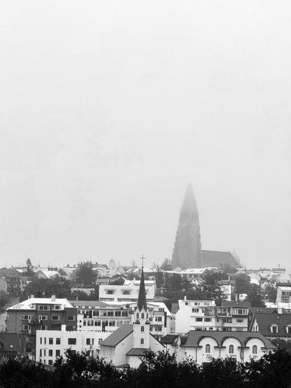 A view of central Reykjavík wihh th Hallgrímskirkja towering over everything. Its gray and a little foggy. 