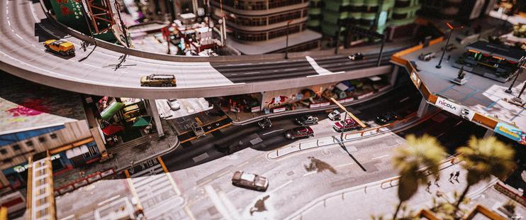 a tilt-shift of a street merging into a boulevard, with an overpass going to an elevated highway