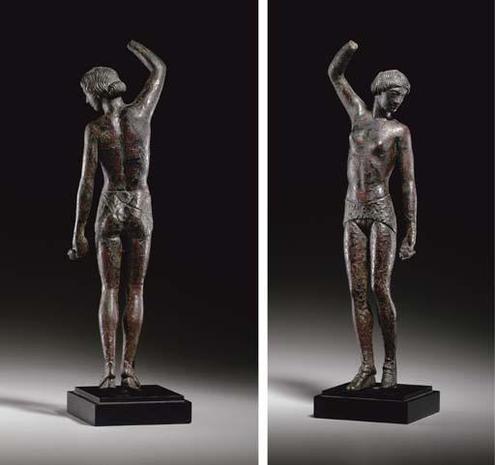 Solid cast bronze figure of a lissome female dancer with elongated torso and legs, nude but for a band-like perizoma covering her buttocks, her pudendum bare, decorated on the reverse with interlocking X's, wearing latchet shoes enclosing her toes and tied at the ankles, standing on her toes, the heels raised (supports below), the right leg slightly advanced, her right arm raised high overhead and bent at the elbow, the left lowered, playing krotala (castanets), one preserved, the dichotomy of …