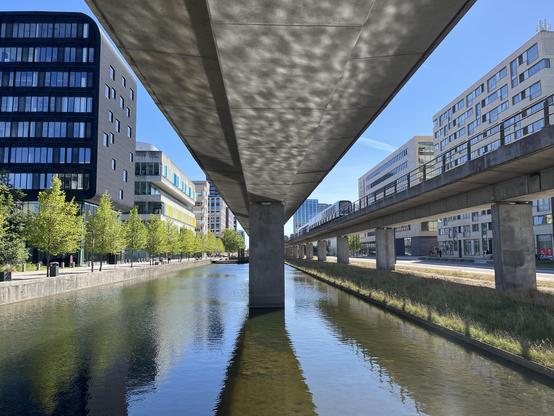 Der in einem Wasserbecken stehende Betonträger der Metro Ørestad, links und rechts moderne Hochhäuser.