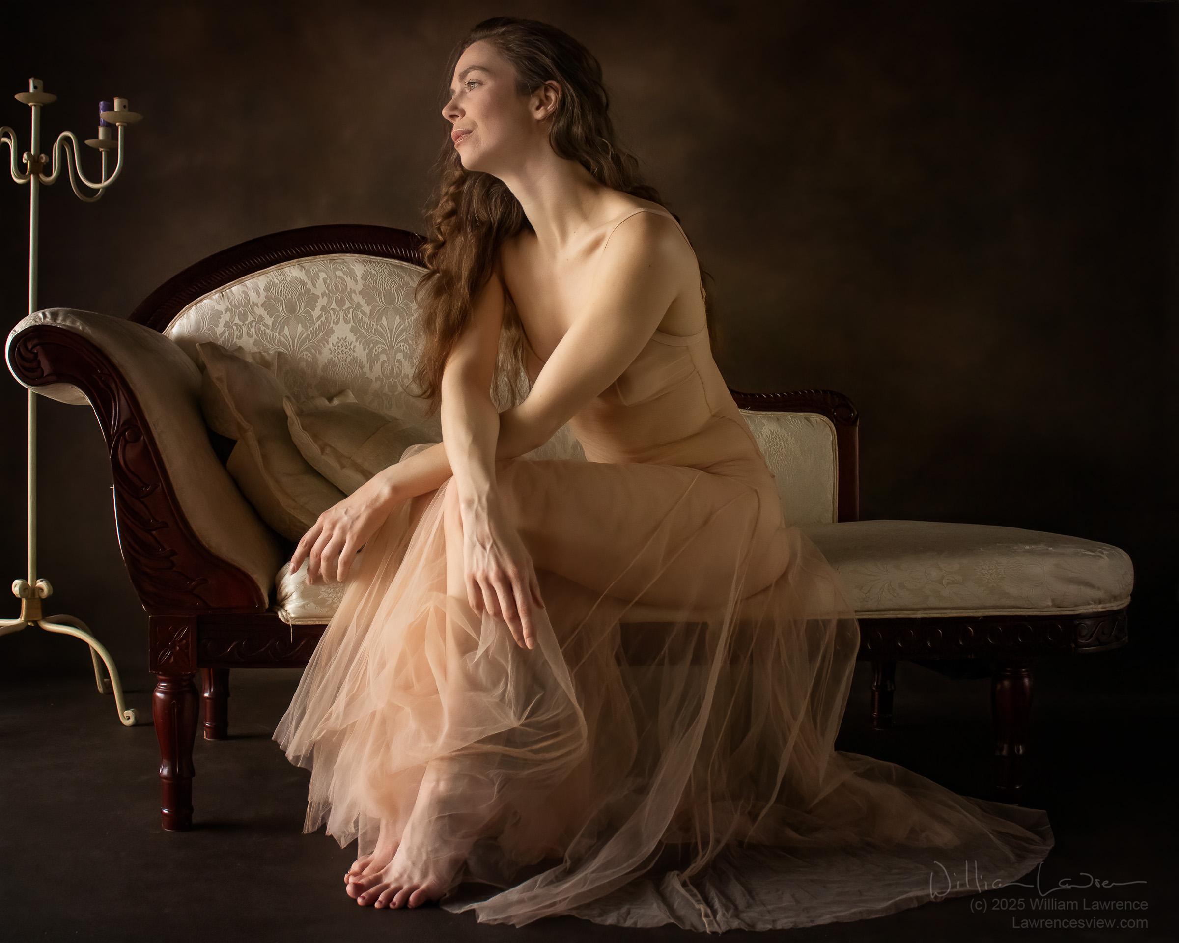 Model Jay ban sits in profile on a chaise, wearing a sheer dress whose skirt billows around her legs. Model Jay ban sits in profile on a chaise, wearing a sheer dress whose skirt billows around her legs.