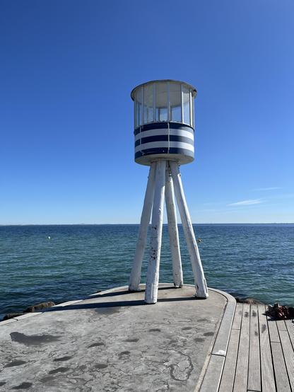 Blau-weißer Bademeisterturm in Klampenborg, hinten blaues Meer.