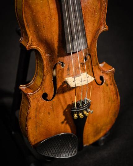 Side angle shot of a violin body showing wear.