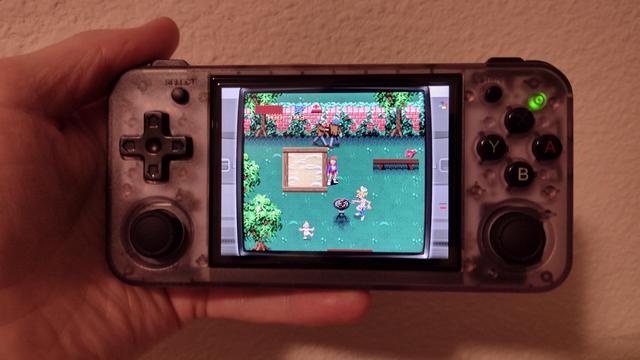 An Anbernic RG35XX handheld game console. The on-screen game is Konami's 'Zombies ate my Neighbors.'