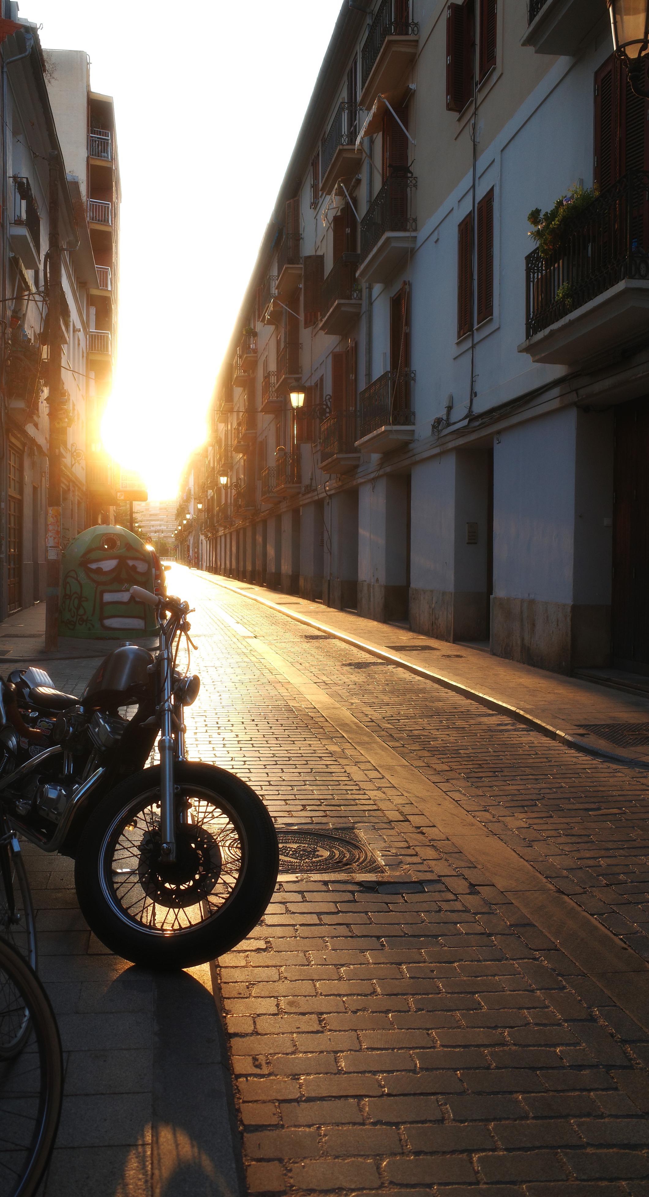 Sun setting seen in a street with a motorbike Sun setting seen in a street with a motorbike