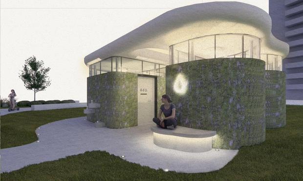 Architects mock-up of an inclusive public toilet facility, that has just won an architecture prize. It has a curvaceous design in natural grey stone, with windows along the top to let daylight in. It is portrayed at dusk, in order to show how it will be lit at night. 