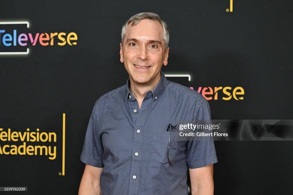 Scott Lowell on the red carpet. He wears a blue shirt with short sleeves.