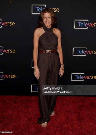 Michelle Clunie on the red carpet. She wears a brown jumpsuit with a light brown leather belt.