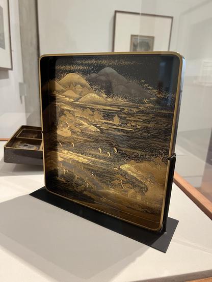 the inside of the lid is also ornately lacquered! There are mountains, birds in flight, trees next to water, a small pagoda at the end of a dock, boats in the water, and a bridge over the water. 