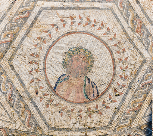 Roman mosaic of Jupiter as Wednesday. The bust of the god is inside a reddish circle. He wears a wreath, possibly an oak-leaf crown. A blue and green himation is draped around his shoulders. Jupiter is depicted as a mature, bearded man.