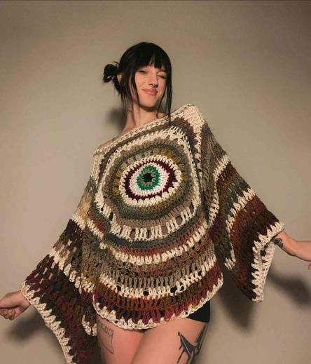 Woman in a colorful, crocheted top with a large eye-like pattern in the center.