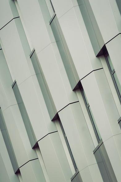 Roughly five tall repetitive modules are lined up diagnonally next to each other from a steel framed building where you can just a see a little bit of the windows embedded in nooks.