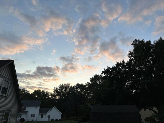 Morning rays of sun painting the East end of the clouds. In the bottom foreground are the back yards of a suburban cul-de-sac.