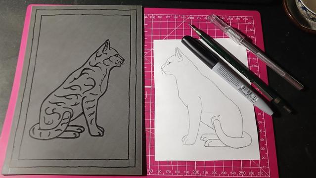 Cat Design on Linoleum. Left is the Cat design transferred onto lino and drawn over with permanent marker. There is extra detail drawn into the cat with permanent marker. To the right is the cat design drawn in pencil, it's juse the outline with no extra detail.