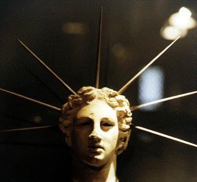 Photo of the head of a sculpture of Helios from his cult centre on the island of Rhodes. He has short, curly hair and seven spikes emerge from his head, as rays of sunlight.