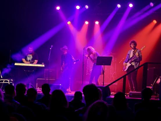 The entire stage with all the members of Frýs on it, with purple and red lights